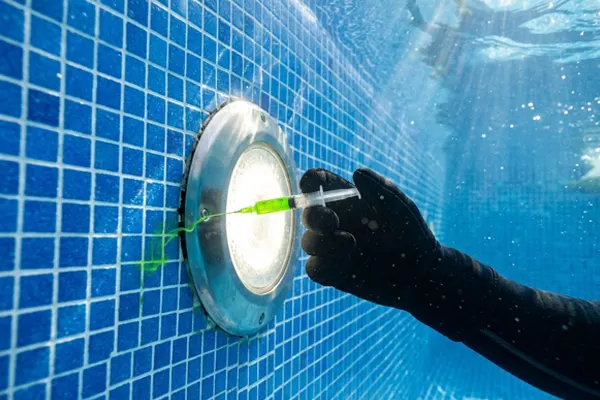 Profesional localizando una fuga en una boquilla de la piscina con tinte