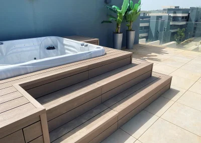 Jacuzzi elevado forrado con madera tecnológica y escalones integrados en una terraza