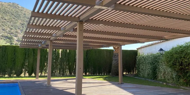 Pérgola de madera tecnológica sobre una tarima junto a una piscina en un jardín