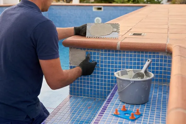 Profesional colocando gresite nuevo en la pared de una piscina