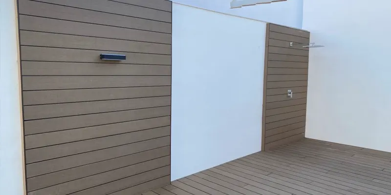 Paredes revestidas con lamas de madera tecnológica y ducha exterior en una terraza