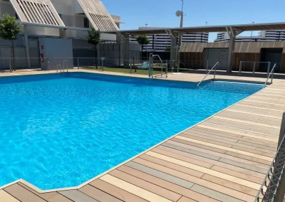 Tarima bicolor de madera tecnológica en la playa de una piscina comunitaria