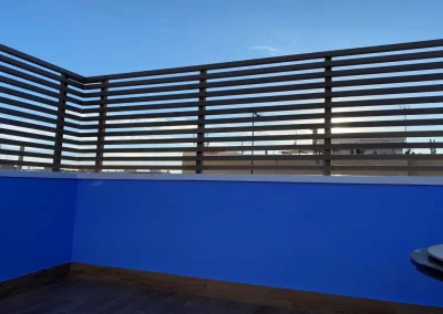 Valla de lamas horizontales de madera tecnológica sobre el muro de una azotea