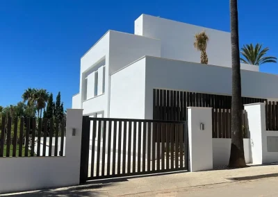 Valla de lamas verticales de madera tecnológica sobre el muro de una vivienda