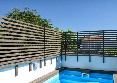 Valla de madera tecnológica de lamas horizontales alrededor de una piscina con tarima