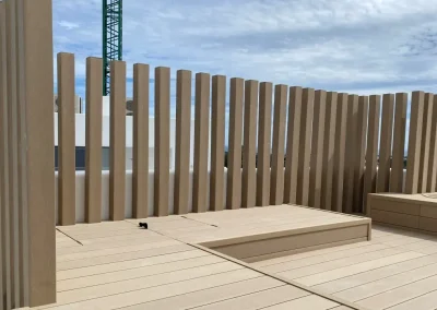 Valla de lamas verticales y tarima de madera tecnológica a juego en una terraza